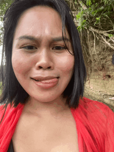 a woman wearing a red top making a funny face