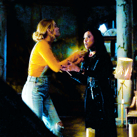 two women standing next to each other in a dark room holding hands