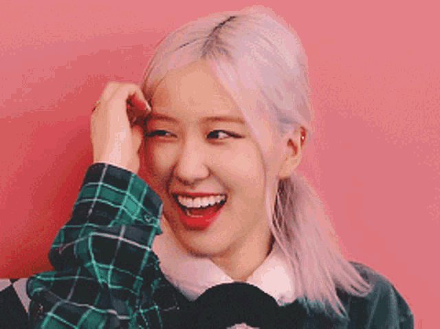 a woman with a plaid shirt on is smiling with her hand on her forehead