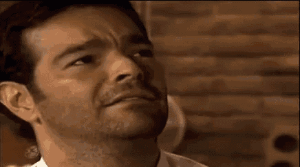 a man with a beard is making a funny face with his mouth open .