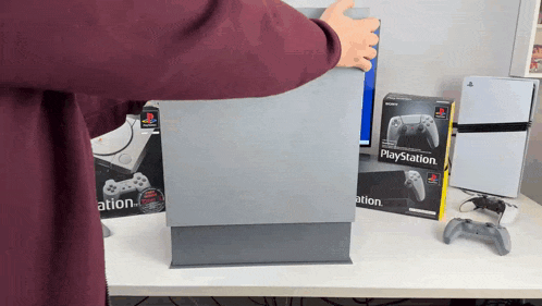 a playstation box sits on a desk next to a person
