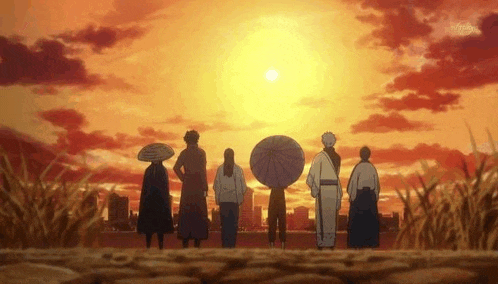 a group of people are standing in front of a sunset .