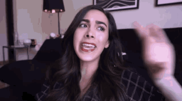 a woman is making a funny face while sitting on a black couch