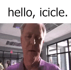 a man in a purple shirt is standing in a room with the words hello , icicle . written above him .