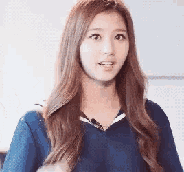 a young woman with long brown hair wearing a blue shirt