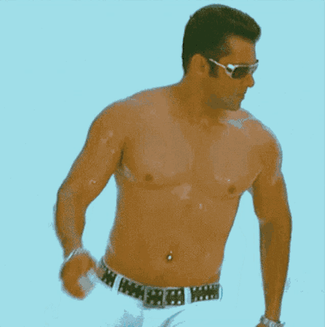 a shirtless man wearing sunglasses and a belly button ring