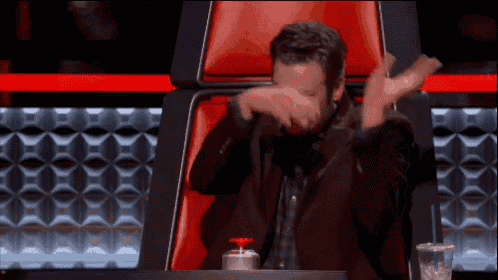 a man in a suit sits in a red chair covering his face