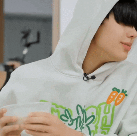 a person wearing a hoodie is holding a cup of coffee .