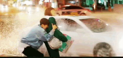 a man is carrying a woman in his arms in the rain .