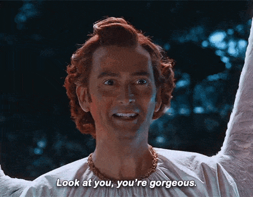a man with red hair and a white shirt says look at you you 're gorgeous