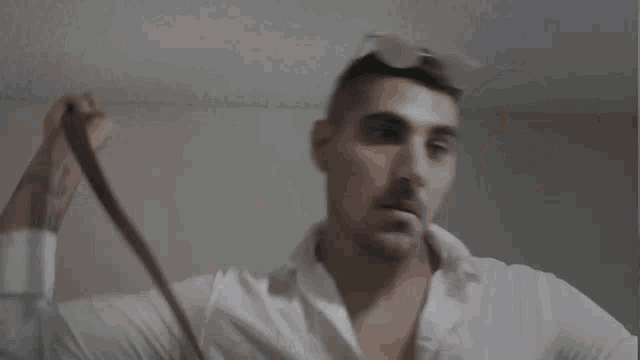 a man in a white shirt is holding a pair of glasses in his hand .