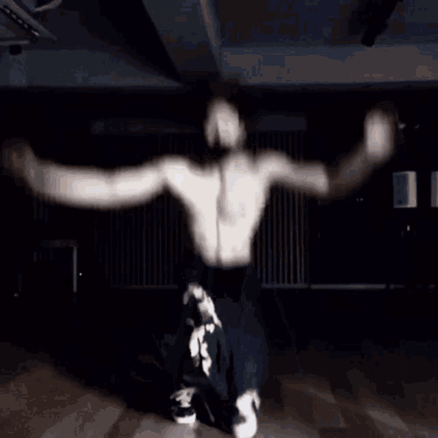 a shirtless man is dancing in a dark room without a shirt on .