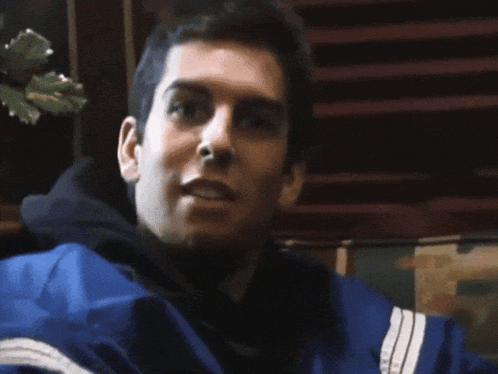 a man in a blue jacket with white stripes on the sleeves is sticking his tongue out