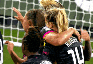 a group of female soccer players are hugging one another and one of them has the number 20 on her jersey