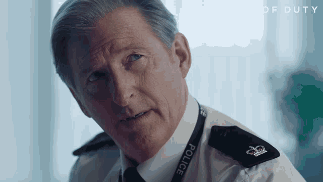 a man with a police lanyard around his neck looks at the camera