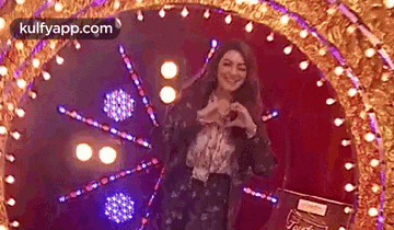 a woman is making a heart shape with her hands in front of a stage .
