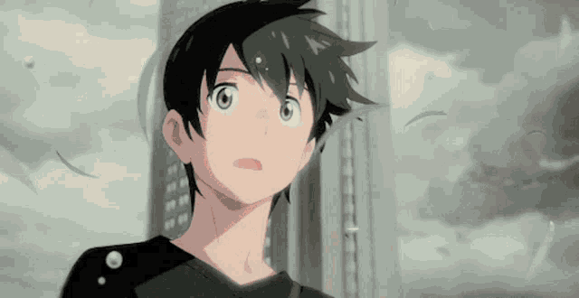 a boy in a black shirt is standing in front of a building and looking up at the sky .