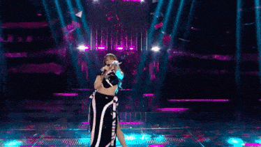 a woman singing into a microphone with her arms in the air