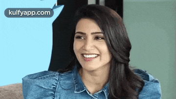 a woman in a blue denim shirt is smiling and looking at the camera .