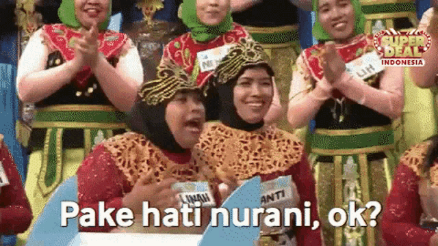 a group of women are clapping and one of them says " oke hati nurani "