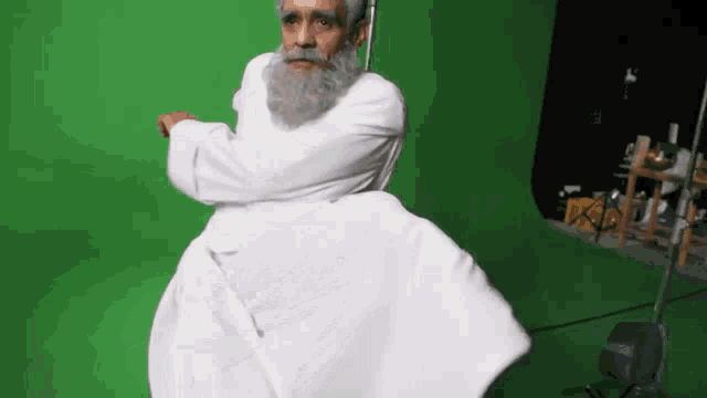 a man with a beard and white robe is dancing on a green screen