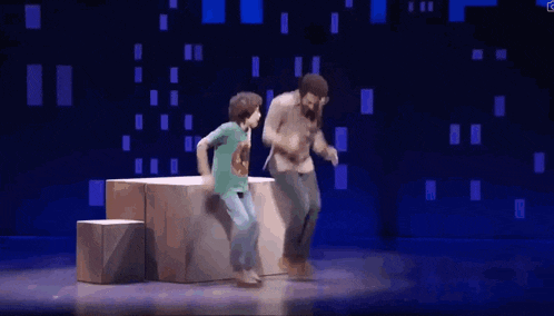 a man and a boy are dancing on a stage in front of a blue background