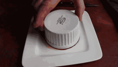 a person is pressing a button on a white plate with a knife