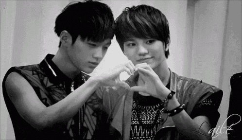 two young men are making a heart shape with their hands in a black and white photo