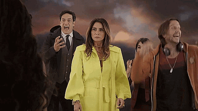 a group of people are standing in front of a cloudy sky and one of them is wearing a yellow coat