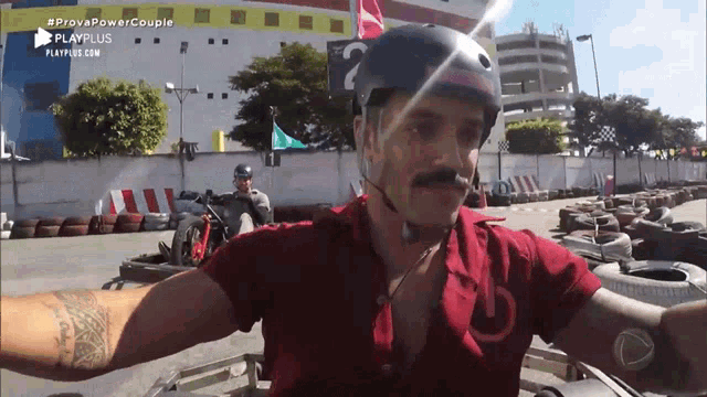 a man wearing a helmet and a red shirt is riding a go kart in a playplus ad
