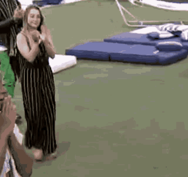a woman in a striped dress is standing on a green carpet .