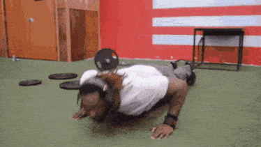 a man is doing push ups in a gym with a weight on his head .