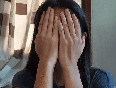 a woman covering her face with her hands while wearing a ring