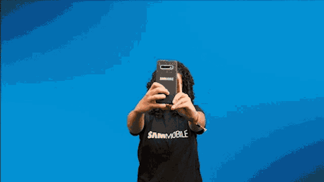 a woman with curly hair is taking a selfie with her cell phone