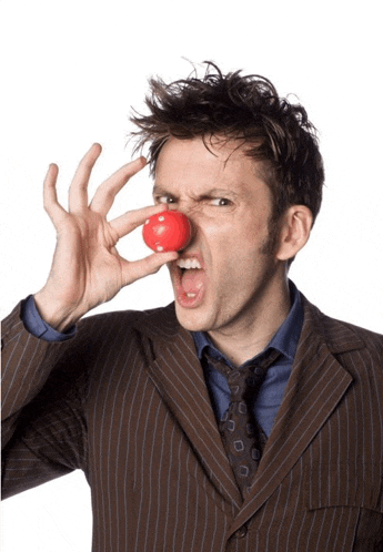 a man in a suit and tie holds a red clown nose