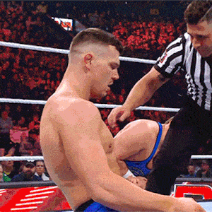 a referee is talking to a wrestler in a ring with a crowd watching