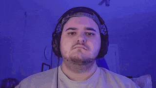a man wearing headphones and a hat is making a face .