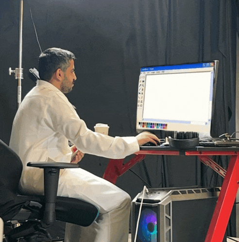 a man in a lab coat sits at a desk with a computer screen that says adobe illustrator
