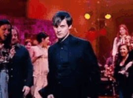 a man in a black suit is standing in a crowd of people .