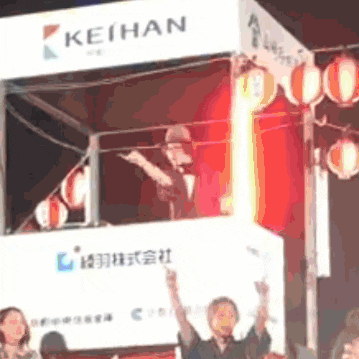 a group of people standing in front of a keihan sign