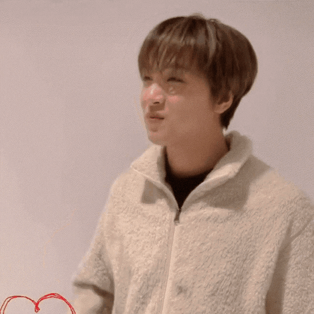 a young man in a white jacket is making a heart with his hands