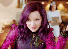 a woman with purple hair is wearing a pink jacket and a purple jacket .