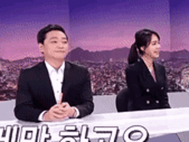 a man in a suit and a woman in a suit are sitting at a table .
