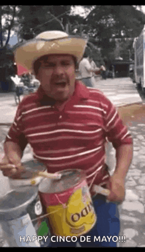 a man wearing a cowboy hat is playing a drum while holding a can of paint .