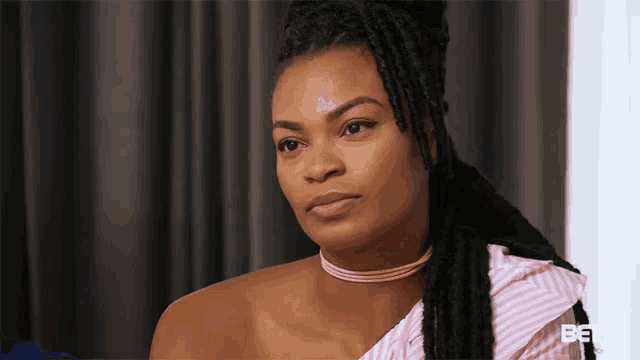 a woman with dreadlocks is wearing a choker and a striped shirt .