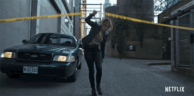 a woman is standing in front of a police car with a n 43 e62 license plate