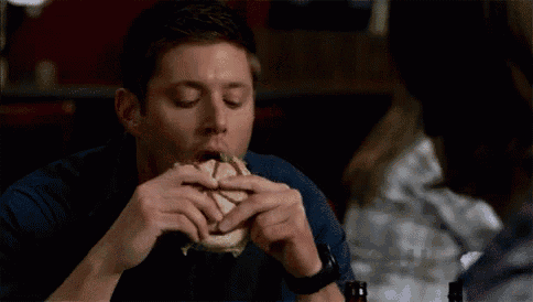 a man is eating a sandwich in a restaurant .