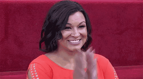 a woman in a red dress is clapping her hands .