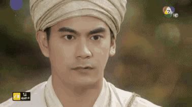 a man wearing a turban and a white shirt looks at the camera .