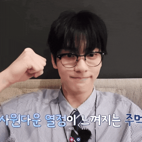 a man wearing glasses and a striped shirt has a fist up in front of his ear